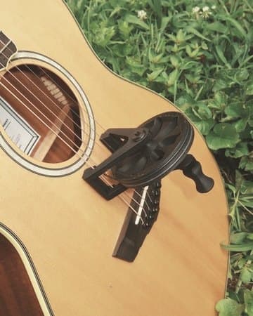 Guitar with Cloverwheel standing against a weathered fence